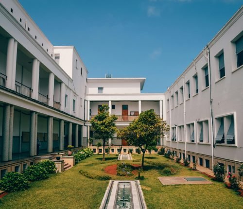 Elegant university building with garden courtyard in Rabat, Morocco under clear blue sky.