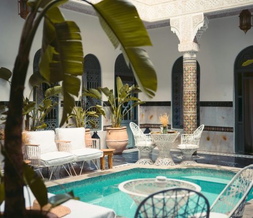 Luxurious Moroccan courtyard in Marrakesh with a pool and ornate decor.